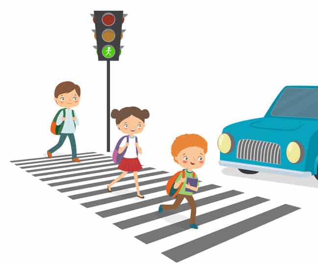 Car brakes while Children cross the road to a green traffic light.
